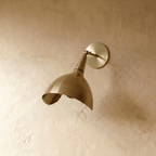 Clérachic wall lamp in brushed brass viewed close, showing the swivel joint and rounded wall plate.