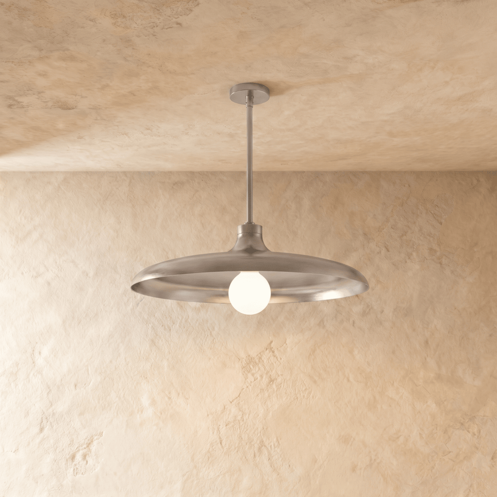 Clérachic pendant light in a bright chrome finish, its wide disc shade and opal glass bulb below a plaster ceiling.