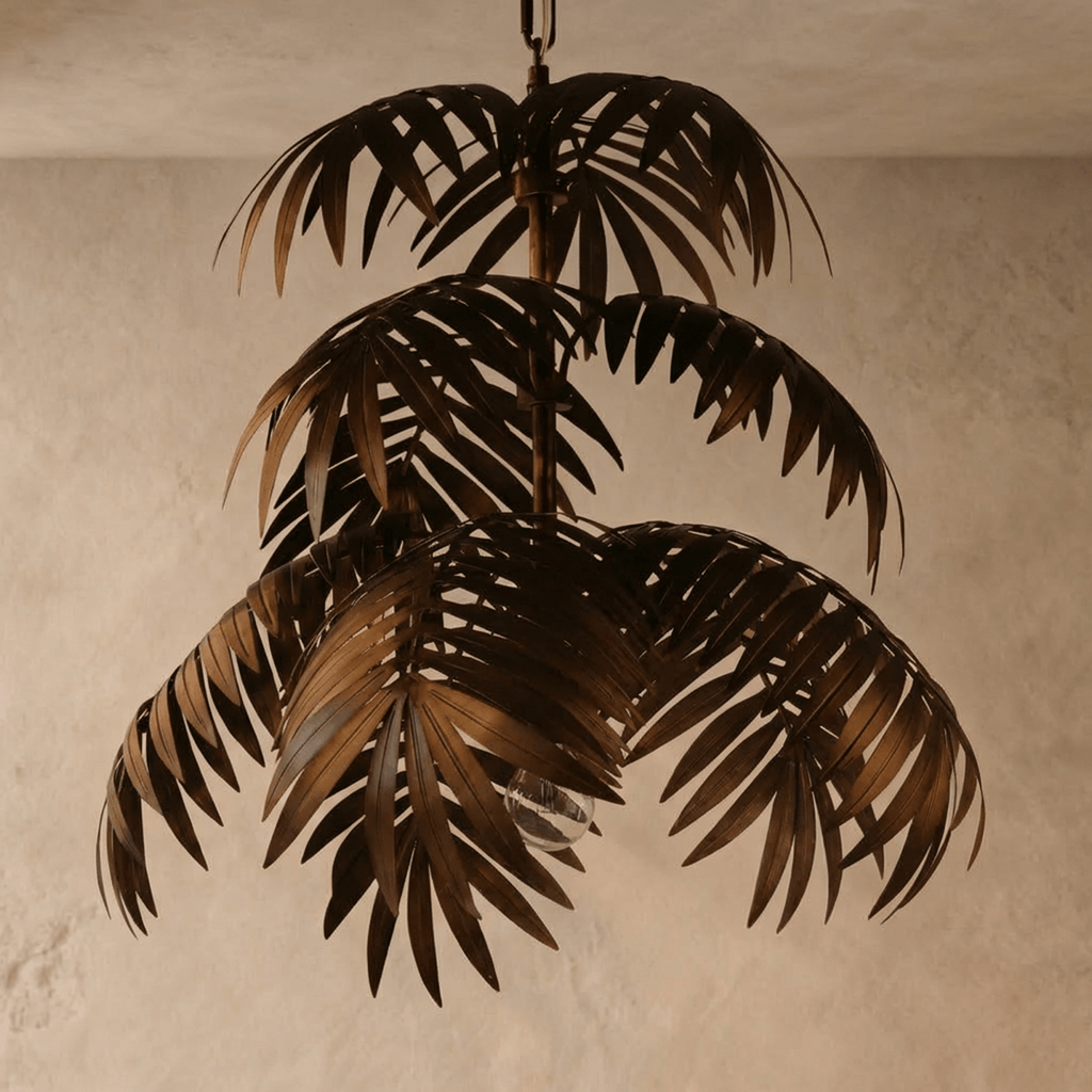 Clérachic tiered palm-leaf chandelier in aged bronze iron, switched off with its clear bulb visible, against limewash.