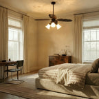 Clérachic dark bronze palm-leaf ceiling light with frosted glass shades, hung over a striped bed in a bright bedroom.