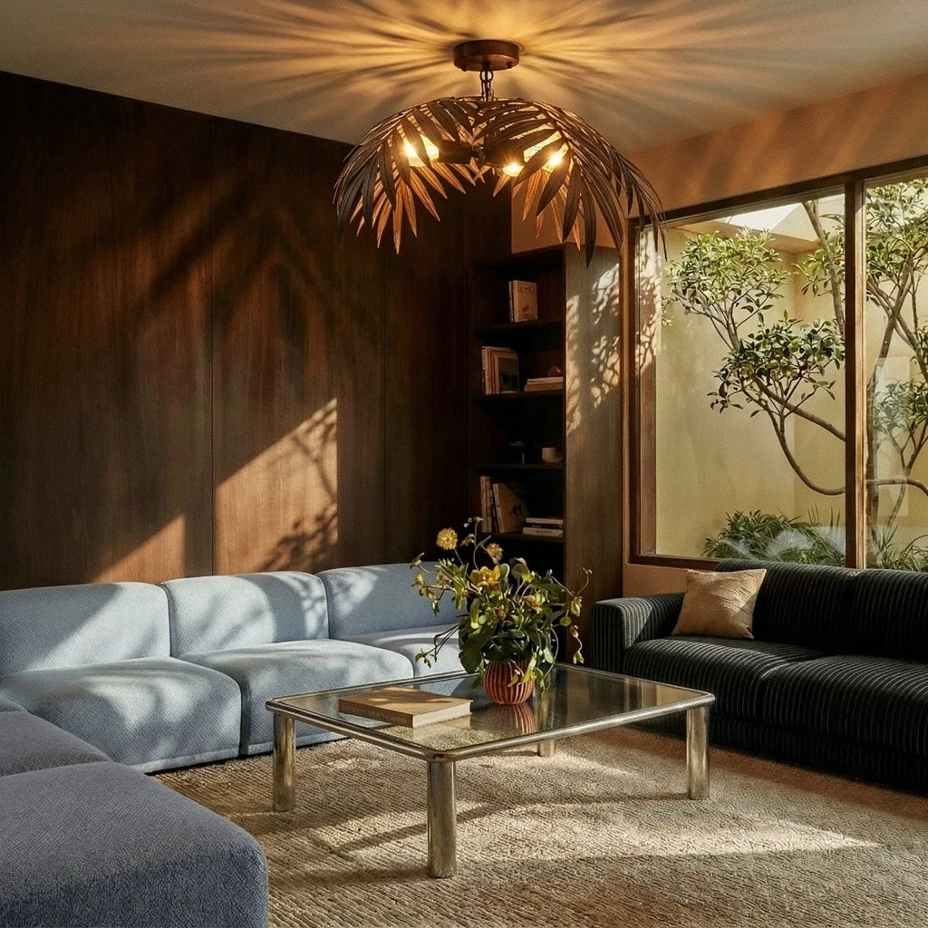 Clérachic ceiling-mounted bronze palm-leaf light casting leaf shadows over a walnut-panelled living room and blue sofa.