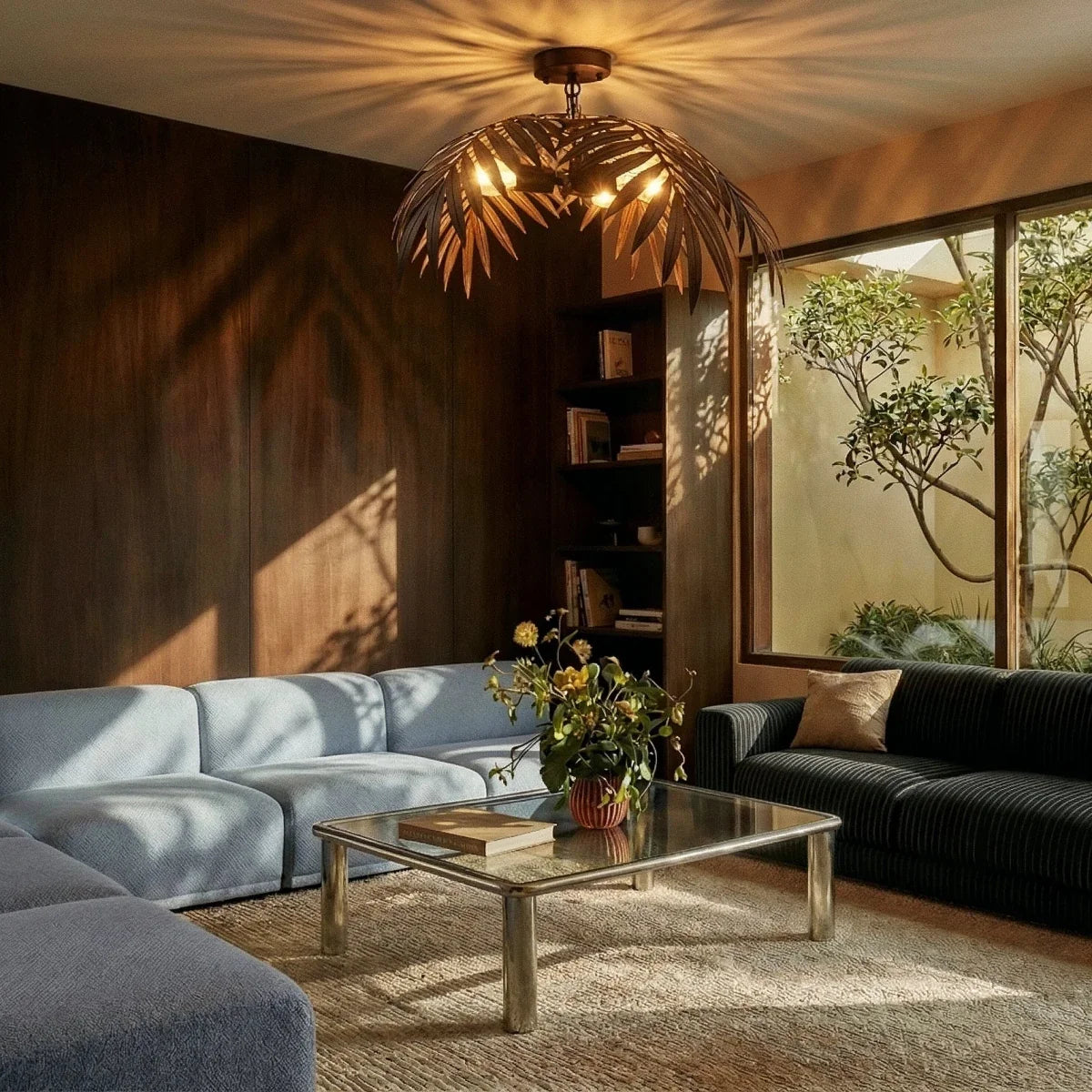 Clérachic ceiling-mounted bronze palm-leaf light casting leaf shadows over a walnut-panelled living room and blue sofa.