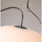 Clérachic close-up of the chrome S-curve arm meeting the cream glass dome on a retro pendant.
