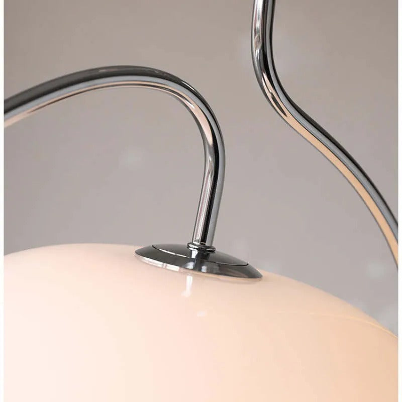 Clérachic close-up of the chrome S-curve arm meeting the cream glass dome on a retro pendant.