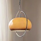 Clérachic amber glass dome pendant with a chrome hoop, hanging beside a sheer curtain.