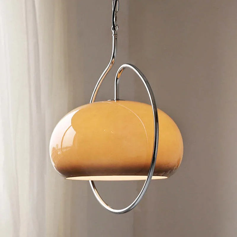 Clérachic amber glass dome pendant with a chrome hoop, hanging beside a sheer curtain.