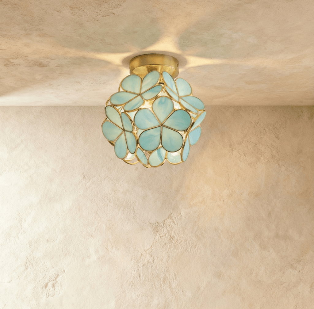 Clérachic flower ceiling light in glossy green glass petals on a brass mount, softly lit on a plaster ceiling.