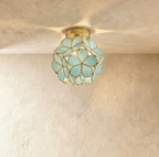 Clérachic flower ceiling light in glossy green glass petals on a brass mount, softly lit on a plaster ceiling.