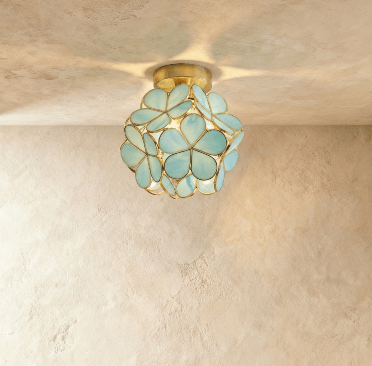 Clérachic flower ceiling light in glossy green glass petals on a brass mount, softly lit on a plaster ceiling.