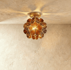 Clérachic flower ceiling light in amber glass petals with an embossed floral pattern, glowing warm overhead.