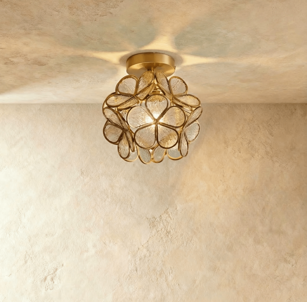 Clérachic flower ceiling light in clear ribbed glass petals on a brass mount, lit warm overhead.