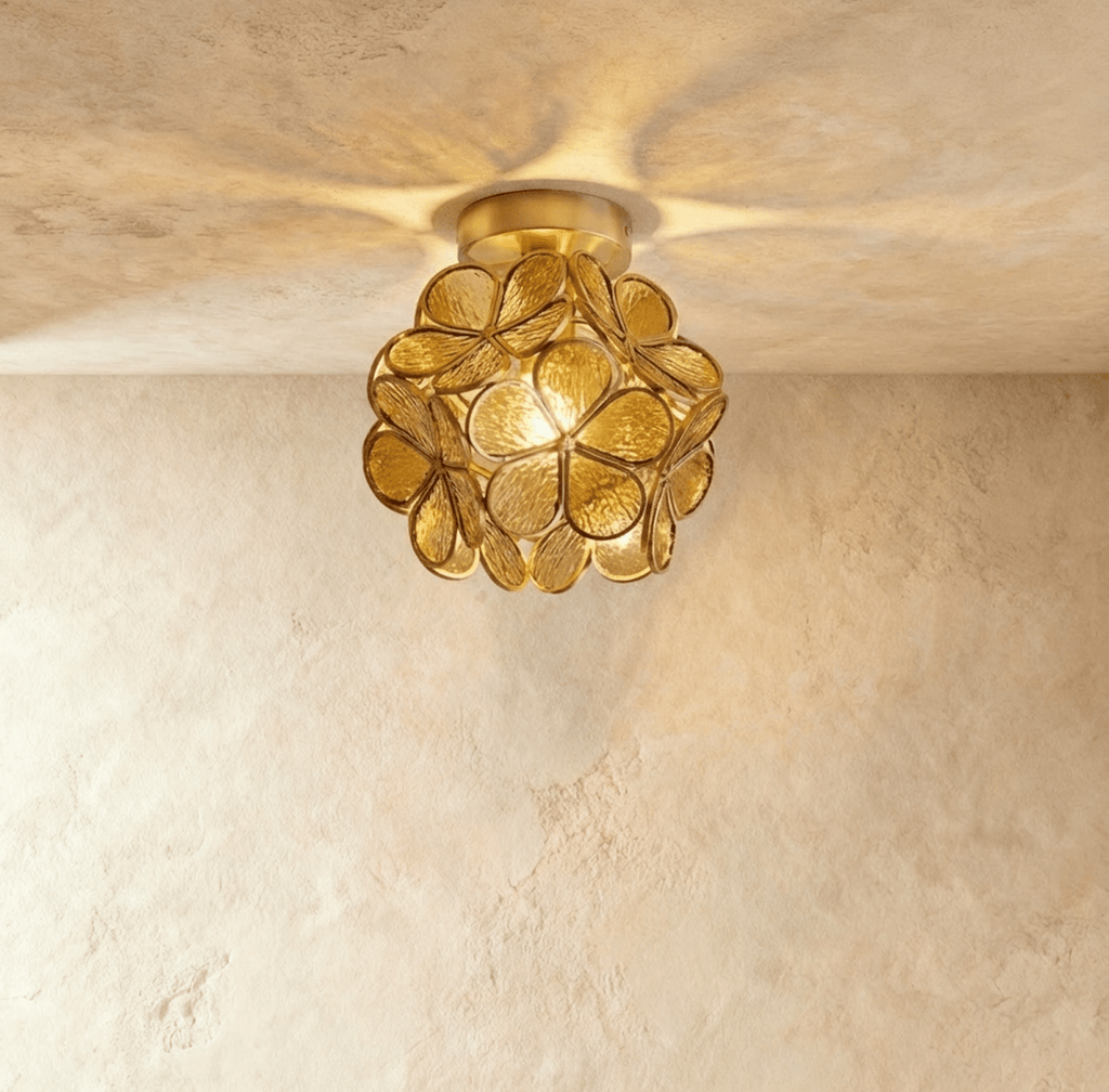Clérachic flower ceiling light in warm amber-brown glass petals on a brass mount, glowing softly overhead.