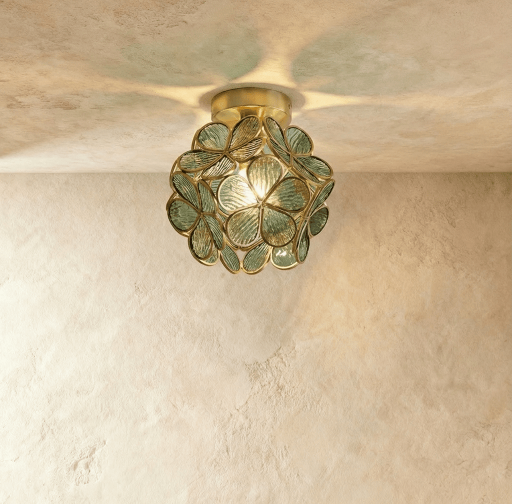 Clérachic flower ceiling light in sage-green ribbed glass petals, glowing warm against a plaster ceiling.