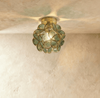 Clérachic flower ceiling light in sage-green ribbed glass petals, glowing warm against a plaster ceiling.