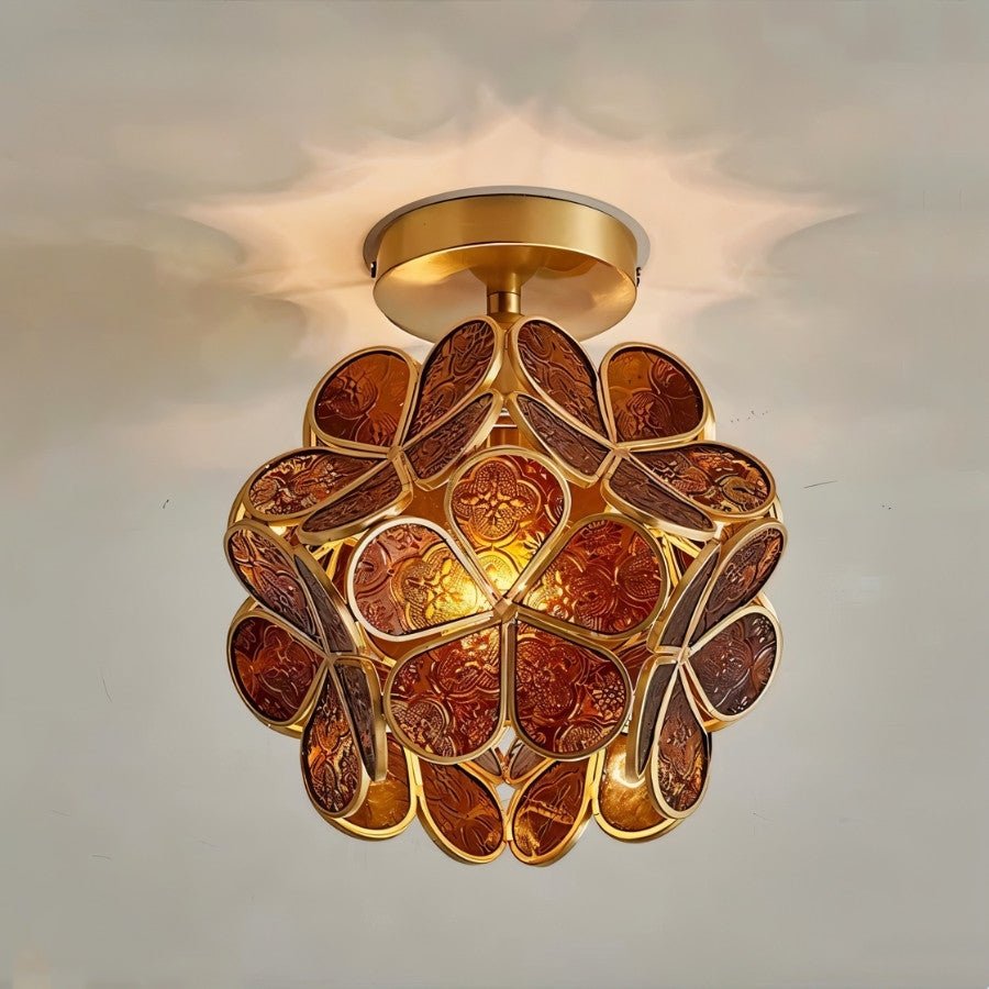 Clérachic flower ceiling light in deep amber glass petals with an embossed floral pattern, lit warm and close.