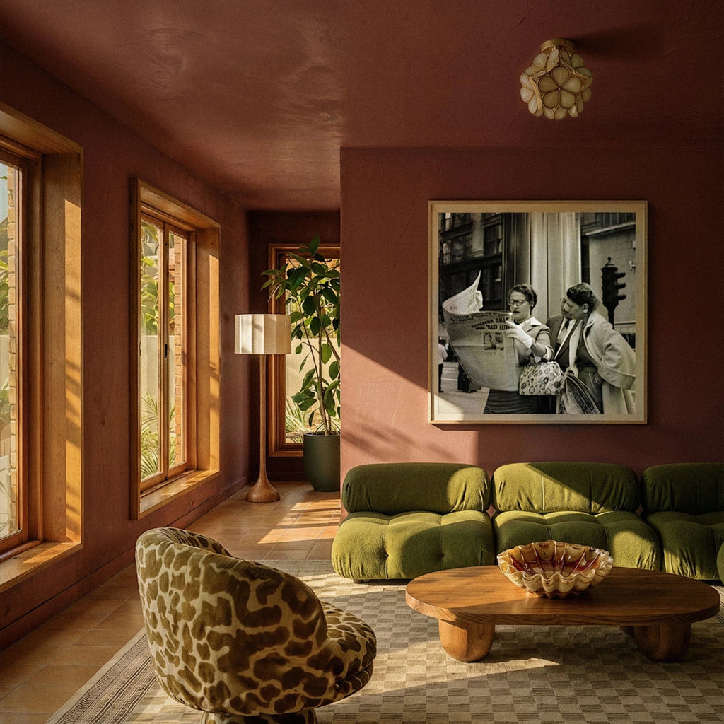 Clérachic flower ceiling light in amber glass overhead in a sunlit terracotta room with a green sofa.