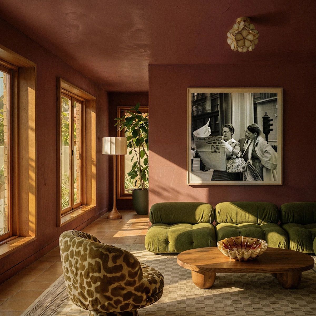 Clérachic flower ceiling light in amber glass overhead in a sunlit terracotta room with a green sofa.