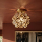Clérachic flower ceiling light in clear ribbed glass petals, lit warm against a warm terracotta ceiling.