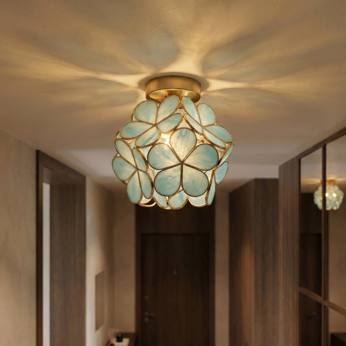 Clérachic flower ceiling light in teal-green glass petals glowing warm above a checkerboard hallway runner.