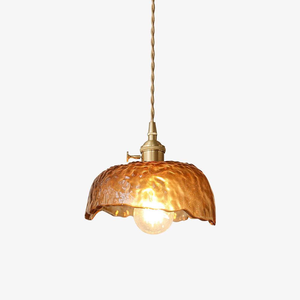 A Clérachic brown glass pendant with a hammered, scalloped dome shade, a brass socket and a twisted cord, lit on a plain white backdrop.
