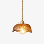 A Clérachic brown glass pendant with a hammered, scalloped dome shade, a brass socket and a twisted cord, lit on a plain white backdrop.