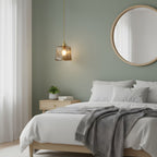 Small Clérachic pendant in brown textured glass hanging beside a bed with white linen, a grey throw and a round mirror on a sage wall.