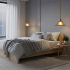 Two Clérachic glass pendants glowing on either side of a bed with a grey throw, in a softly lit bedroom with a slatted wall panel.