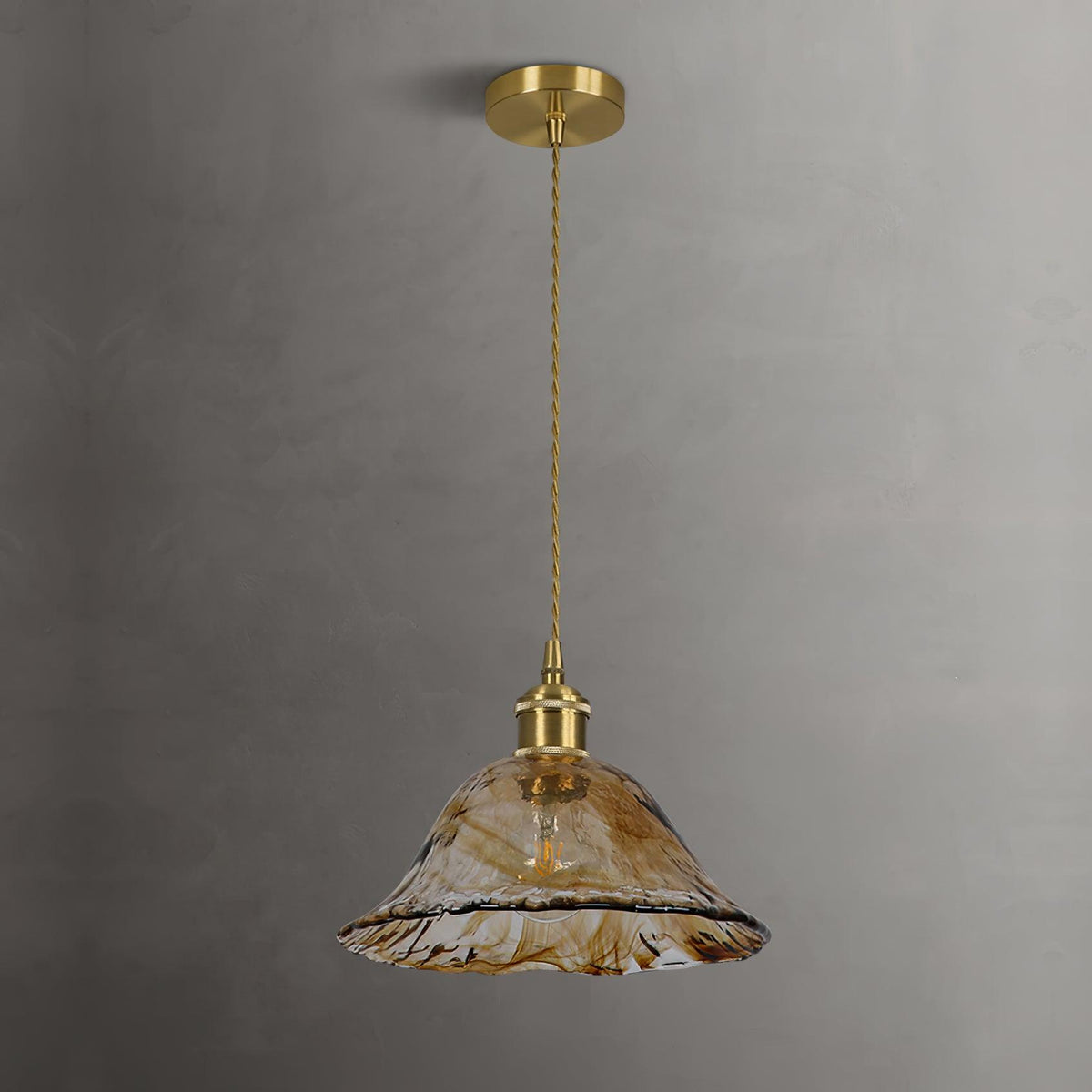 Unlit Clérachic bell-shaped pendant with a brass ceiling plate against a grey wall, its rippled brown glass edge lightly frilled.
