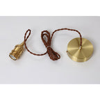 Brass socket, twisted brown cord and round ceiling plate of this Clérachic pendant, laid out flat on a pale background.
