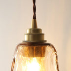 Close view of the brass socket and twisted brown cord at the top of this Clérachic pendant, above the rippled glass shade.