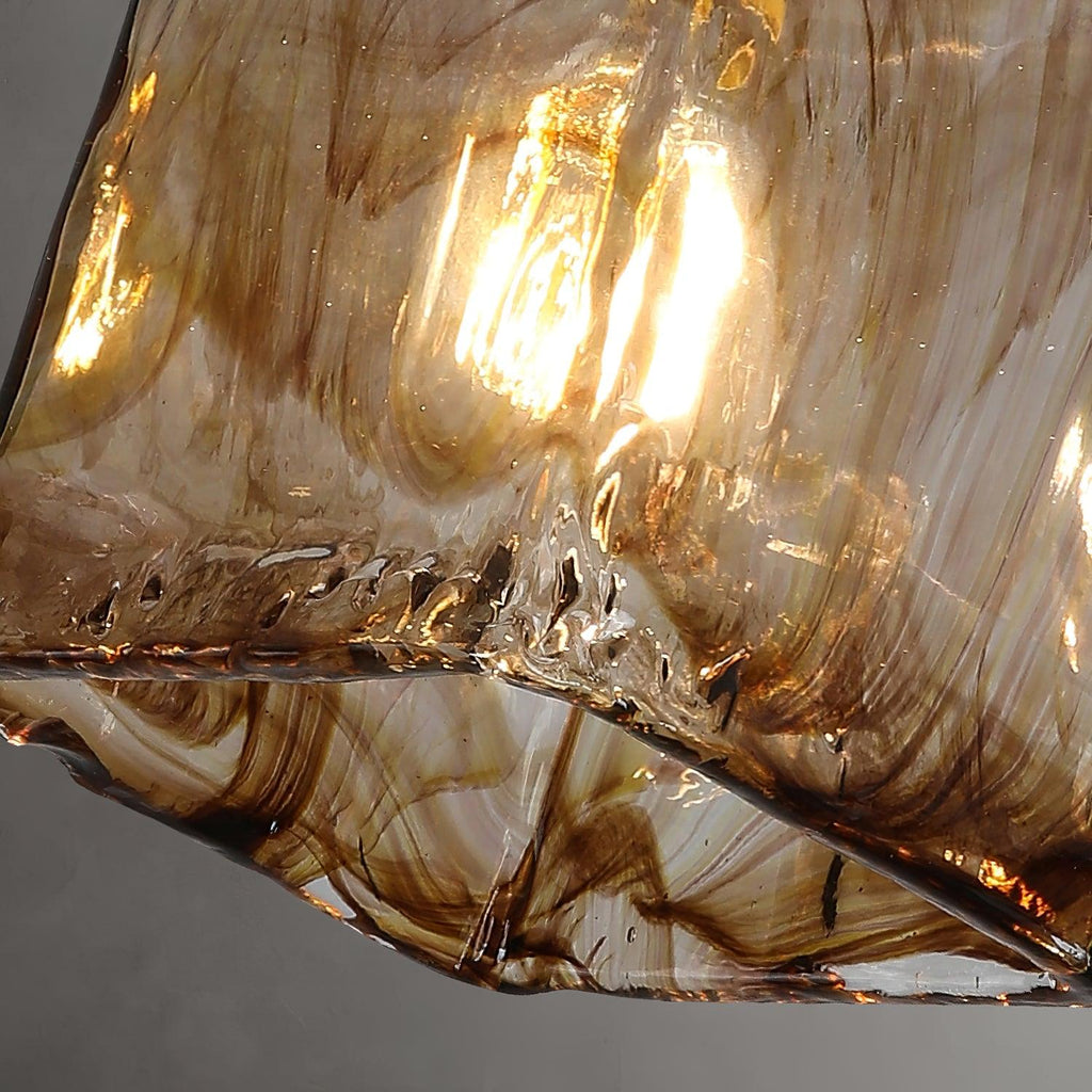 Underside of this Clérachic pendant's glass shade, with swirls of dark brown running through the lit amber glass.