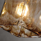 Underside of this Clérachic pendant's glass shade, with swirls of dark brown running through the lit amber glass.