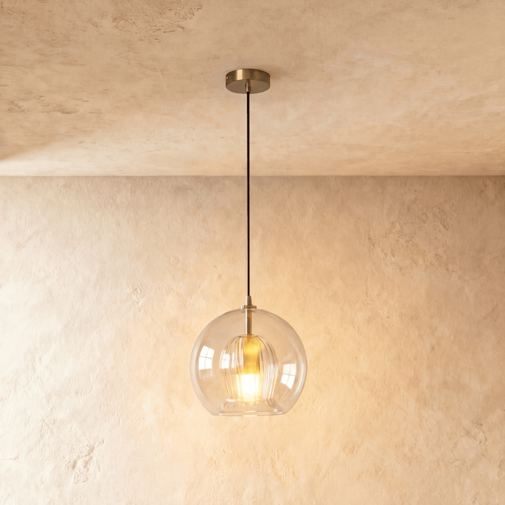Clérachic pendant light close-up on the knurled brass ceiling rose and black cord above the glass globe shade.