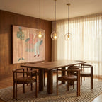 Three Clérachic pendant lights lit warm above a walnut dining table, brass fittings against dark wood panelling.