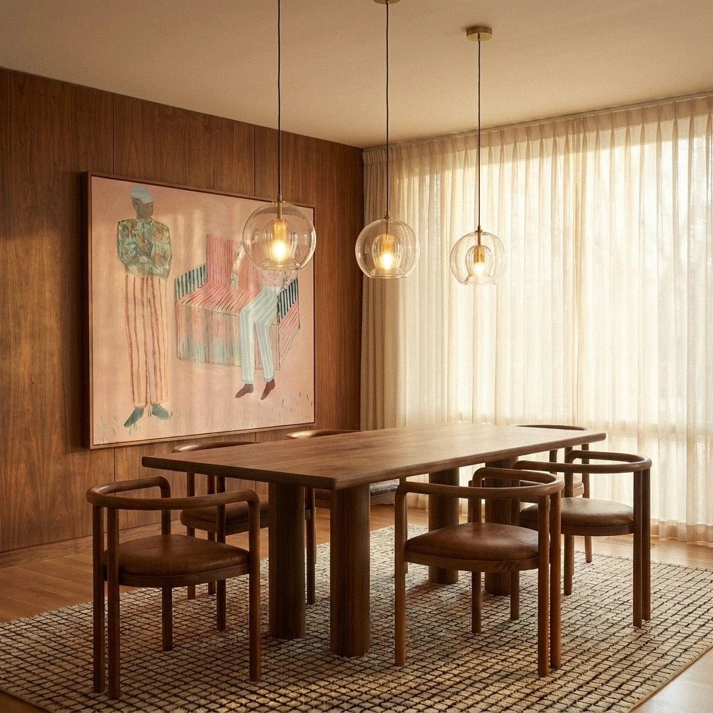 Three Clérachic pendant lights lit warm above a walnut dining table, brass fittings against dark wood panelling.