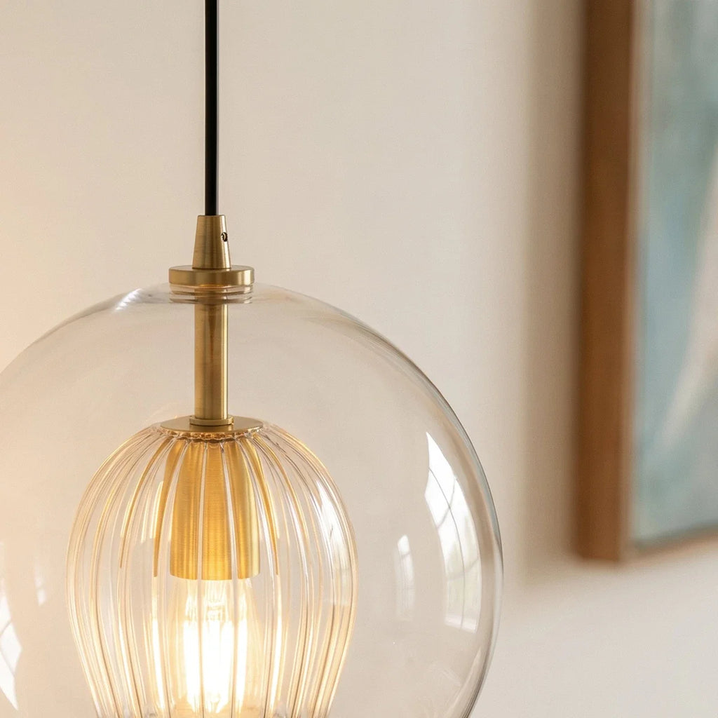 Clérachic pendant light close-up on the brass fitting and fluted glass shade nested inside the clear outer globe.