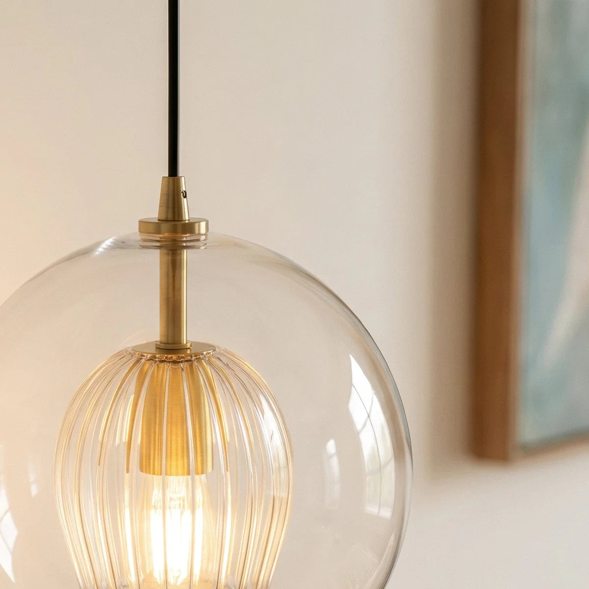 Clérachic pendant light close-up on the brass fitting and fluted glass shade nested inside the clear outer globe.