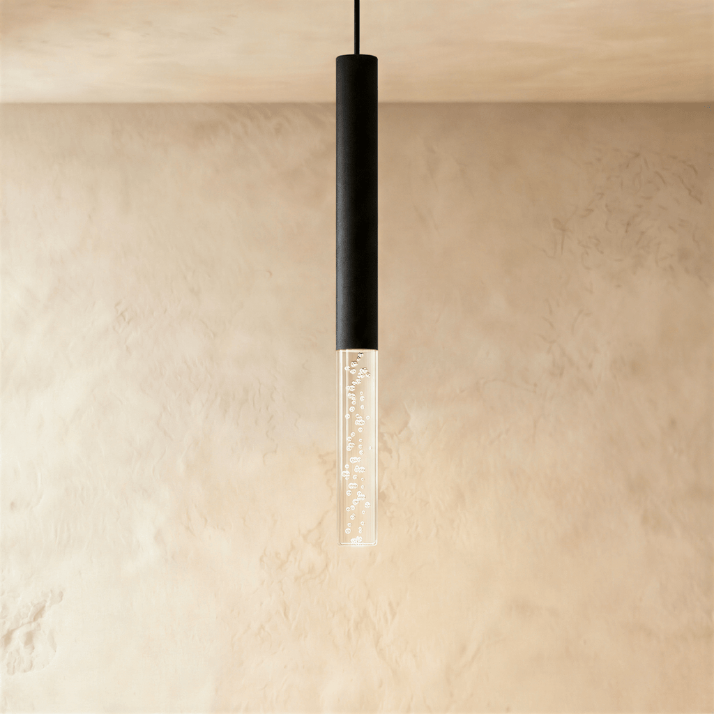 Clérachic slim pendant light with a black aluminium tube and a clear bubble acrylic shade, hung against limewash walls.