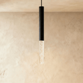 Clérachic slim pendant light with a black aluminium tube and a clear bubble acrylic shade, hung against limewash walls.