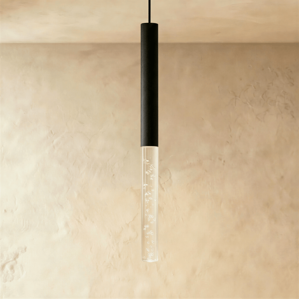 Clérachic black cylinder pendant light with an extended clear acrylic shade full of tiny bubbles, shown on a plaster wall.