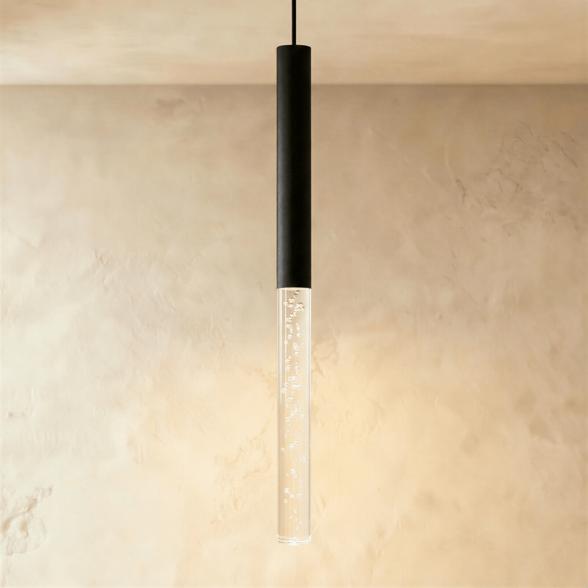 Clérachic black pendant light with the longest bubble acrylic shade, its warm glow washing across a limewash wall.
