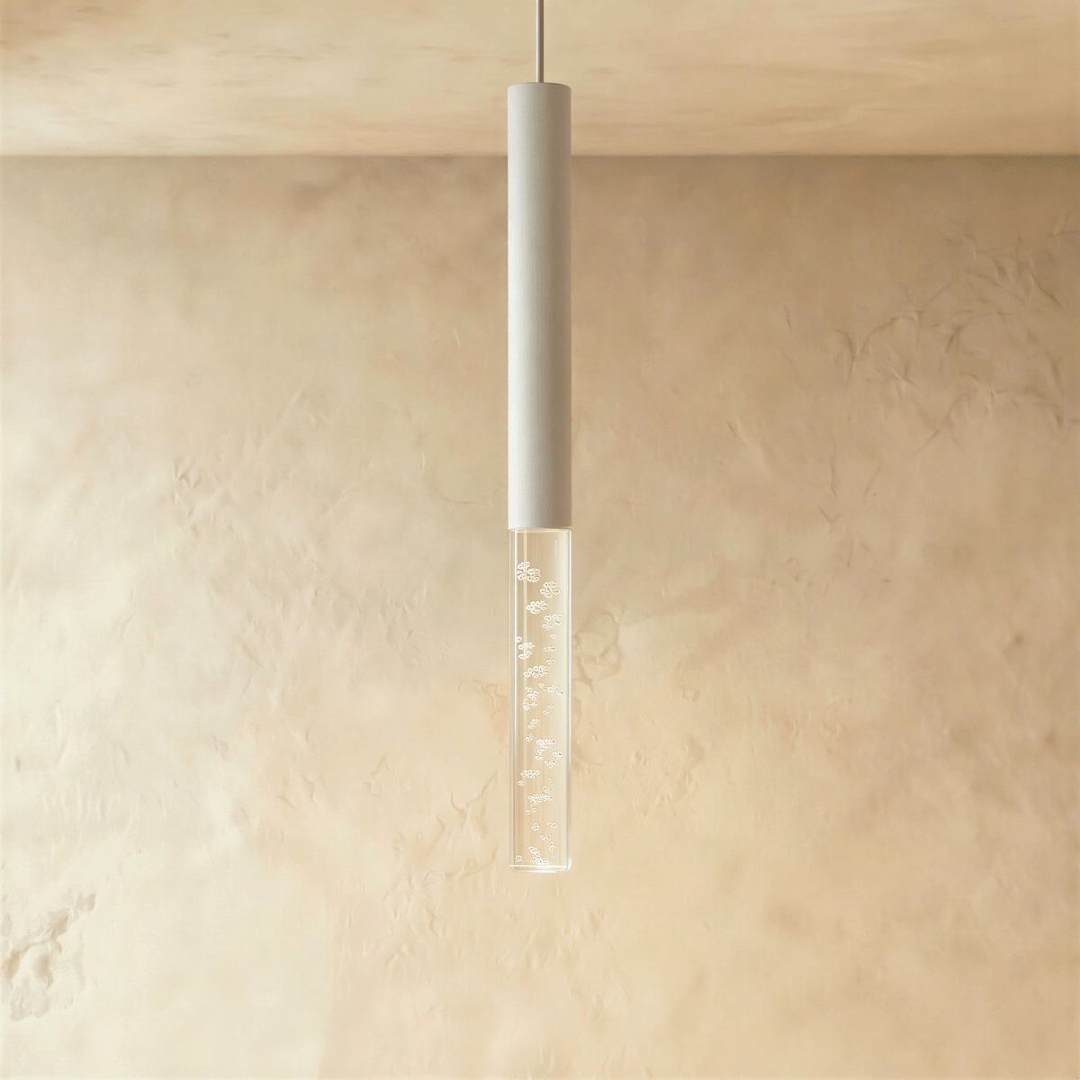 Clérachic slim white cylinder pendant with a clear acrylic shade of sparkling bubbles against a soft plaster wall.