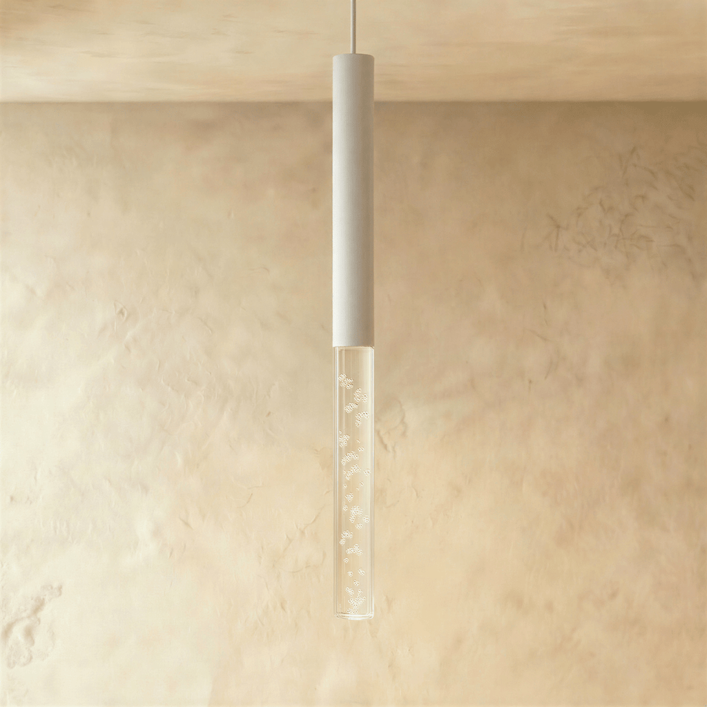 Clérachic white tube pendant light with a longer bubble acrylic shade, lit warmly against a limewash wall.