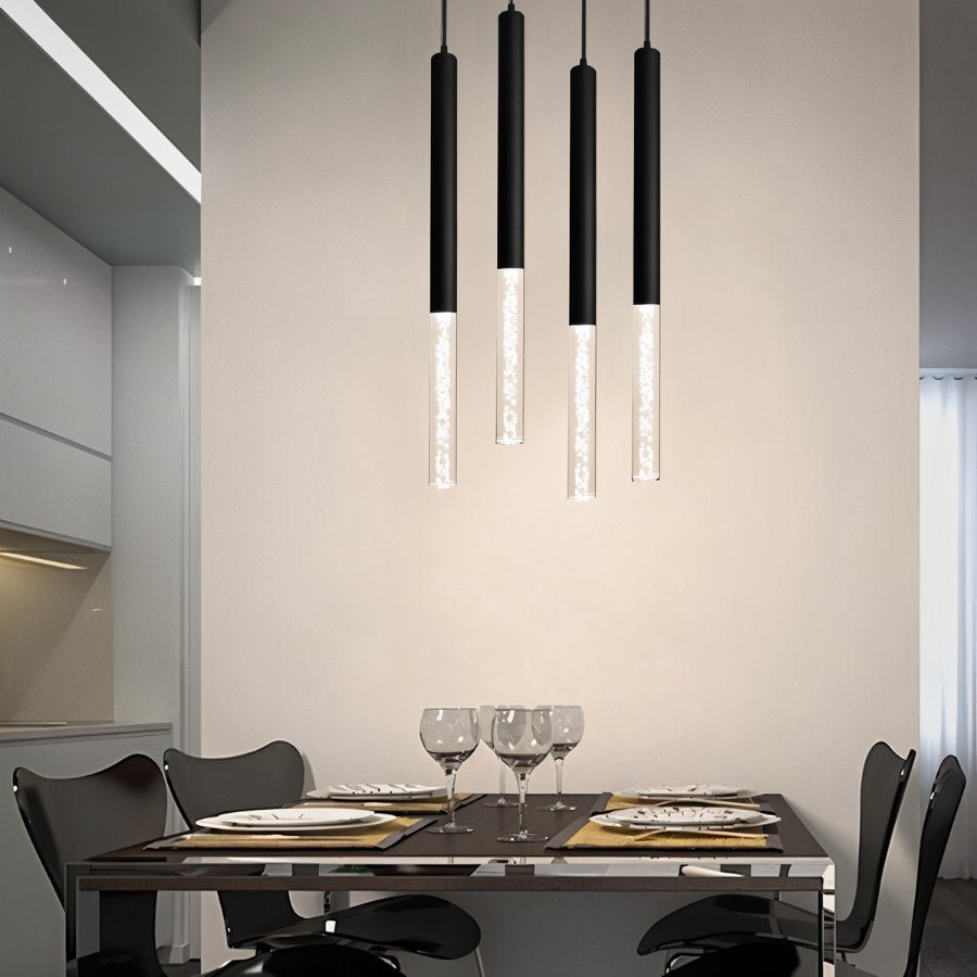 Four Clérachic black pendant lights with bubble acrylic shades hung at staggered heights above a dining table.