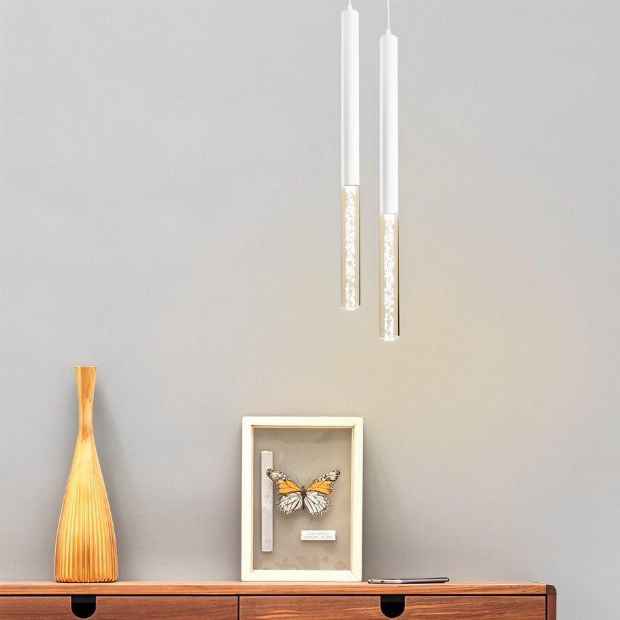 Two Clérachic white pendant lights with bubble acrylic shades hanging above a wooden sideboard and framed butterfly.
