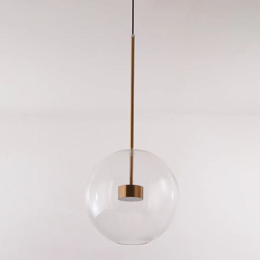 The Clérachic Bubble Cluster Pendant Light in its single clear-glass globe version, hanging on a slim brushed-brass rod.