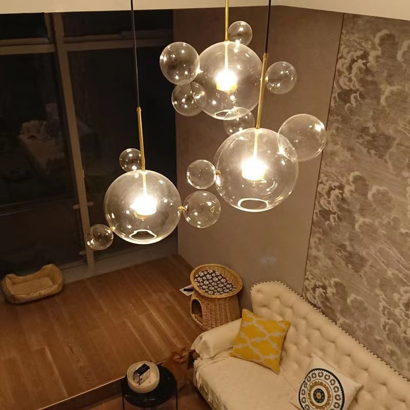 The Clérachic Bubble Cluster Pendant Light's 4-head clear-glass cluster lit above a tufted cream sofa in a loft-style living room.