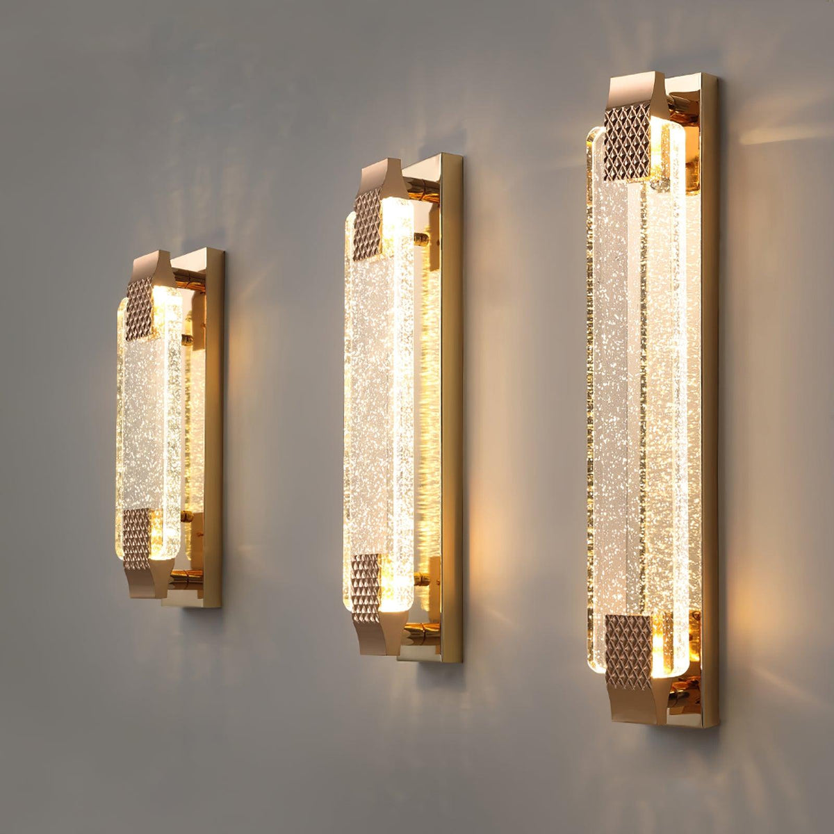 Three lengths of this Clérachic bubble-crystal wall light side by side on a grey wall, each glowing warmly.