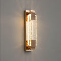 Three-quarter view of the rose gold backplate and bubble crystal of this Clérachic wall light, lit against a grey wall.
