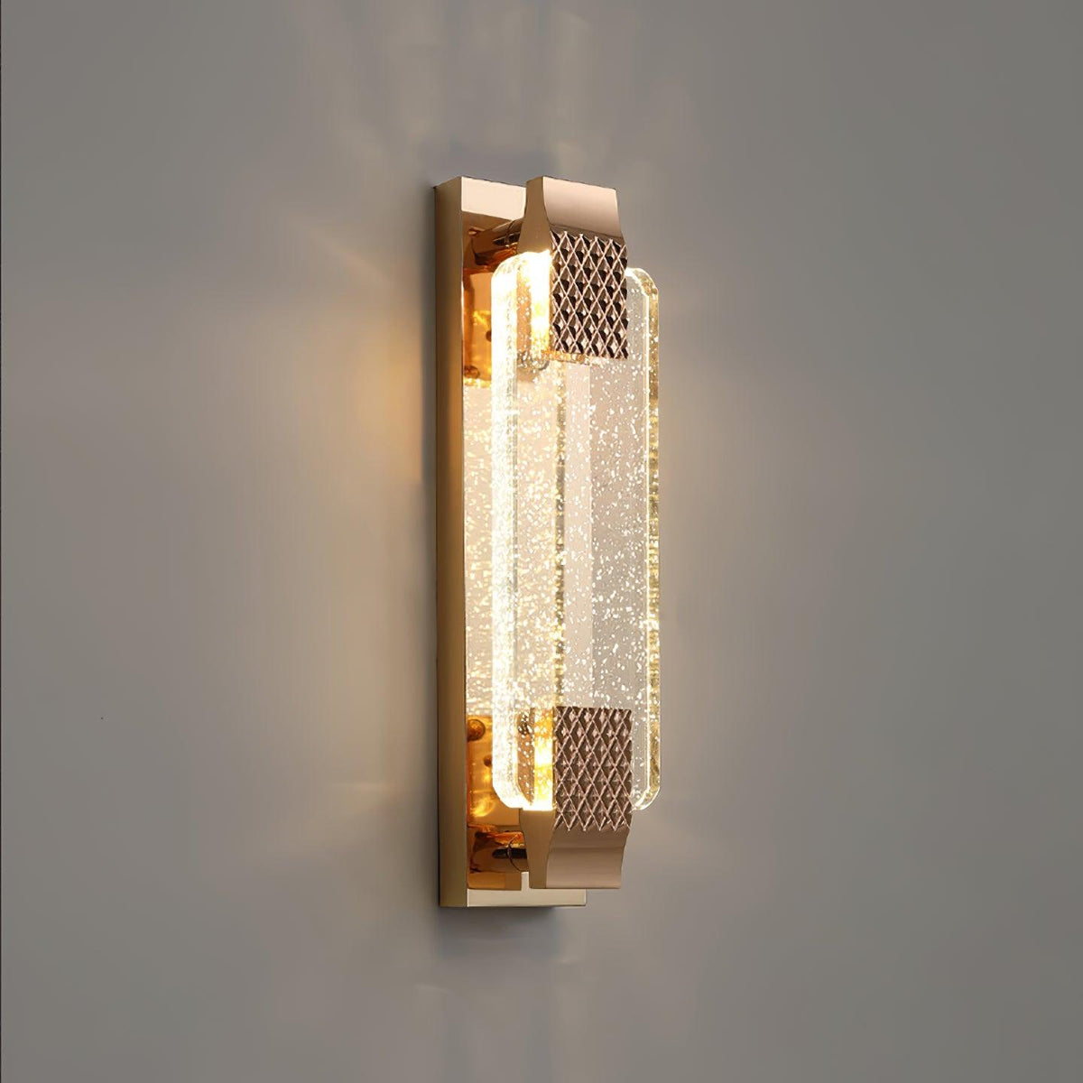 Three-quarter view of the rose gold backplate and bubble crystal of this Clérachic wall light, lit against a grey wall.